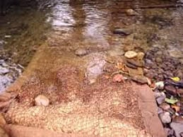Natural-fibre sediment mat in a watercourse